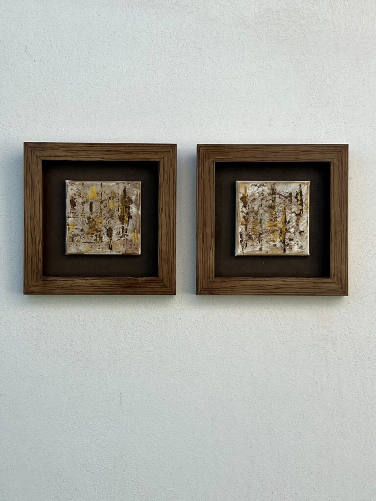 Café, dos lienzos pequeños pintados con café en cajas de madera oscura, obra de Olga García López, vista general en pared